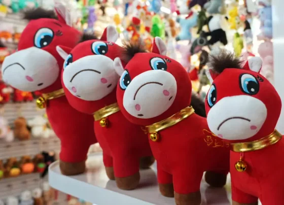 Quatro cavalos de pelúcia com expressão triste. Eles são vermelhos e têm um colar dourado com um sino.