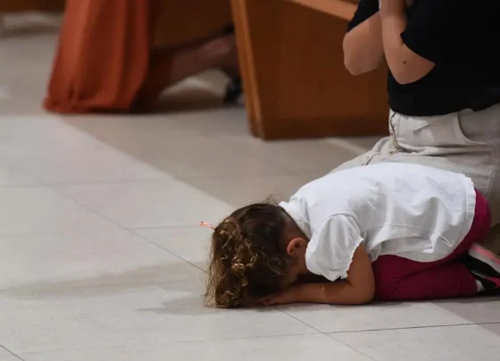 Imagem mostra criança acompanhada da mãe durante missa