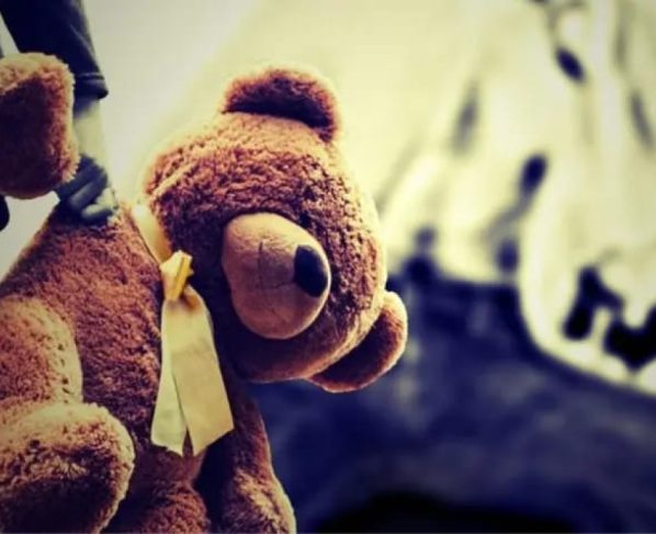 Imagem colorida de uma criança segurando um urso de pelúcia - Metrópoles